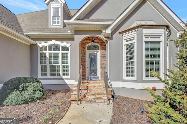 property entrance with a shingled roof, stone siding, and stucco siding