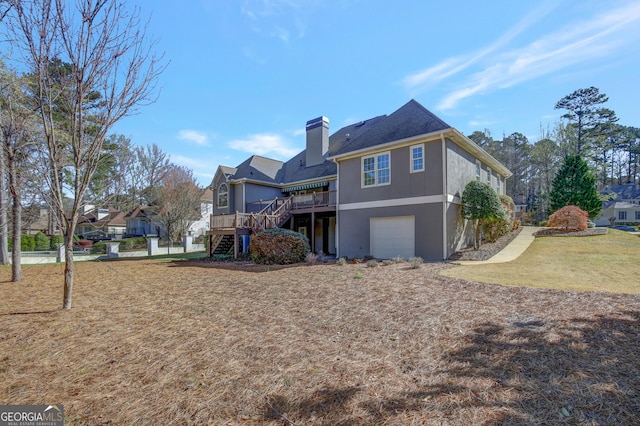 back of house featuring a garage, a lawn, a chimney, and stairs