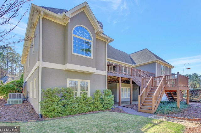 rear view of property with a wooden deck, a shingled roof, stairs, stucco siding, and central air condition unit