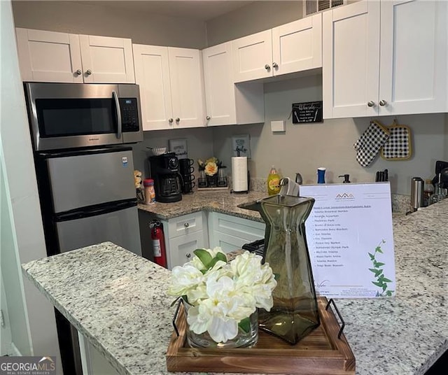 215 Piedmont Ave NE Unit 2205, Atlanta, GA 30308 - kitchen with stainless steel microwave, a sink, visible vents, white cabinets, and light stone countertops