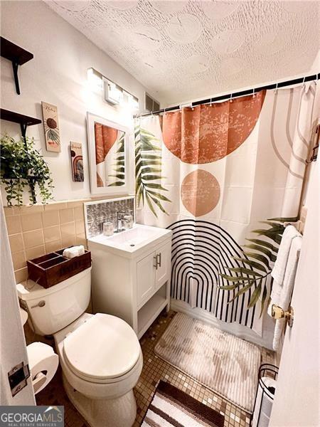 215 Piedmont Ave NE Unit 2205, Atlanta, GA 30308 - bathroom with tile walls, a textured ceiling, toilet, vanity, and tile patterned flooring