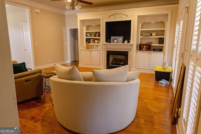 430 Brantley Rdg, Warner Robins, GA 31088 - living area with ornamental molding, a tiled fireplace, ceiling fan, built in shelves, and light wood finished floors