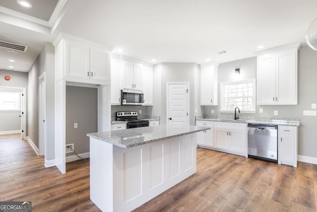 kitchen featuring a sink, appliances with stainless steel finishes, wood finished floors, and white cabinets