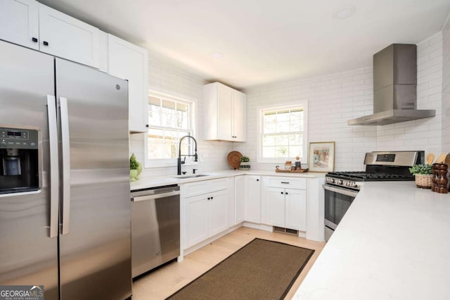 kitchen with tasteful backsplash, appliances with stainless steel finishes, light countertops, and wall chimney range hood