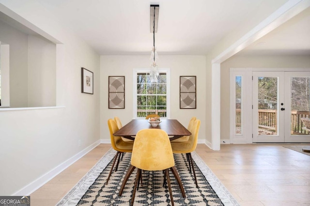 dining room featuring french doors, light wood-type flooring, and baseboards