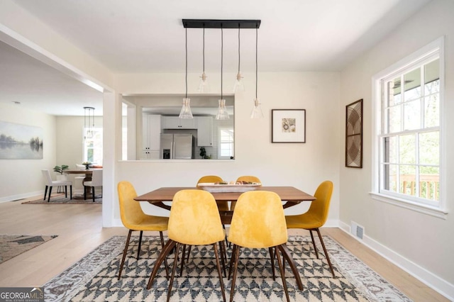 dining area with a wealth of natural light, visible vents, baseboards, and wood finished floors