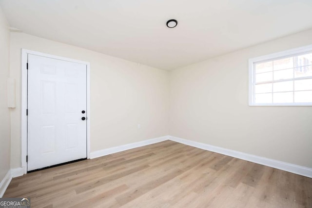 unfurnished room with baseboards and light wood-style floors