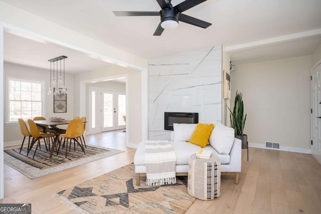living room with a ceiling fan, wood finished floors, visible vents, and baseboards