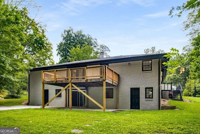 rear view of house with a yard, brick siding, a wooden deck, and a chimney