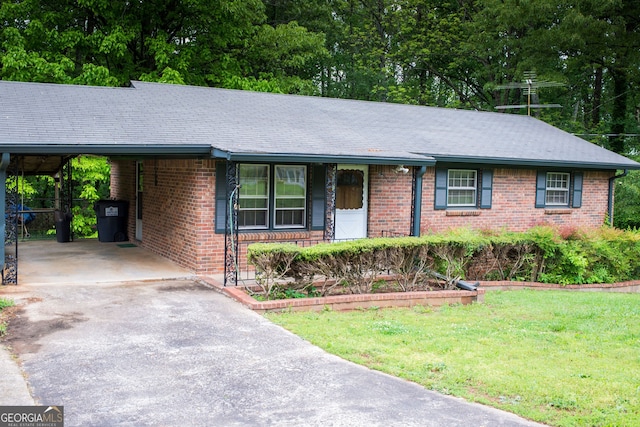 ranch-style home with an attached carport, a front yard, brick siding, and aphalt driveway