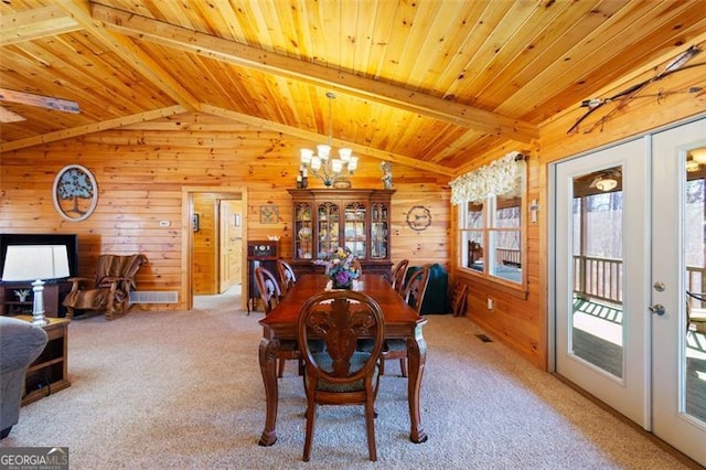 dining area featuring lofted ceiling with beams, wooden walls, french doors, and wood ceiling