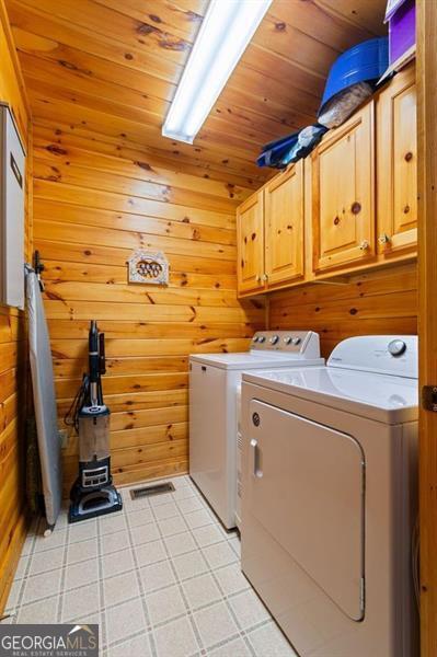 laundry area with wood walls, independent washer and dryer, wooden ceiling, and cabinet space