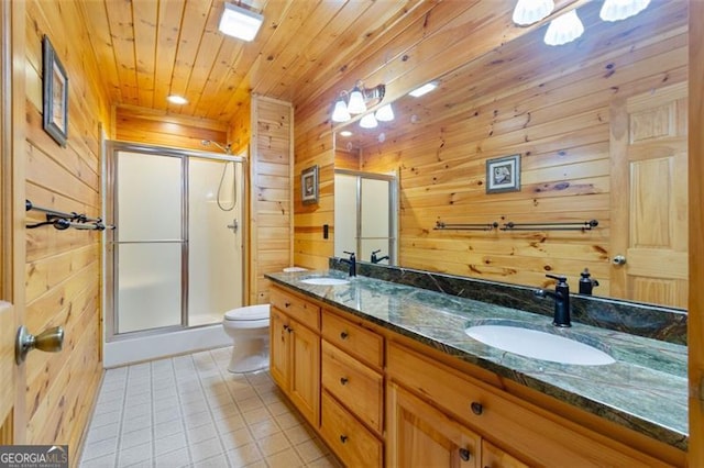 bathroom with wood walls, tile patterned flooring, a shower stall, and a sink