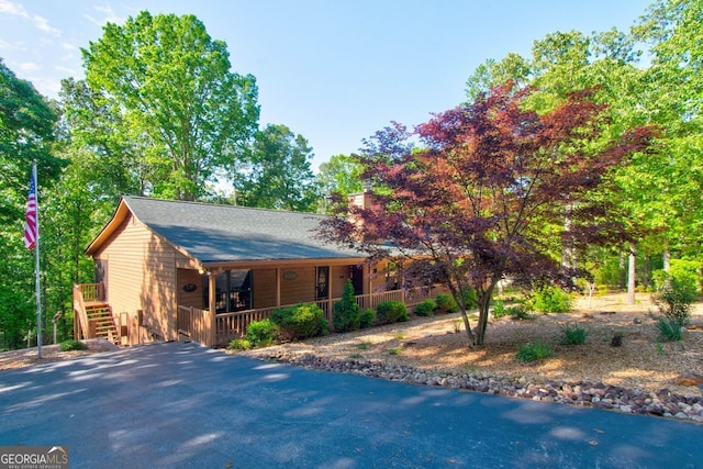 view of front facade with a porch, stairway, a chimney, and driveway