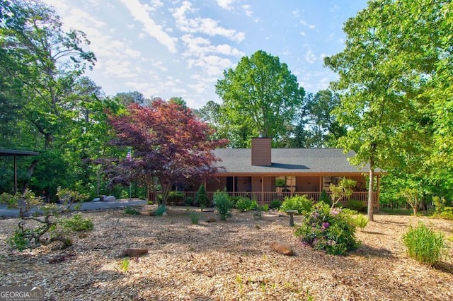 back of house with a chimney and covered porch