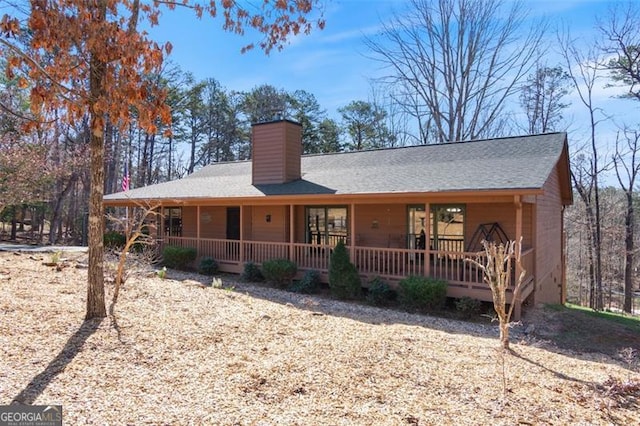 view of front of home featuring a shingled roof, a porch, and a chimney