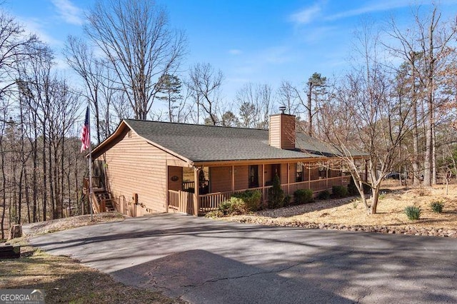 view of front of house with a chimney, driveway, and a porch