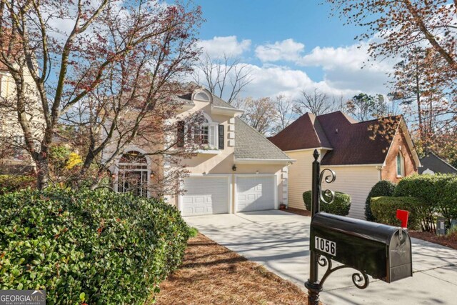 view of front of home featuring roof with shingles, driveway, and stucco siding