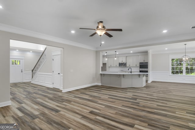 243 Barrington Oaks Dr, Brunswick, GA 31523 - unfurnished living room with stairway, crown molding, a ceiling fan, a sink, and dark wood-style flooring