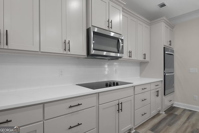 243 Barrington Oaks Dr, Brunswick, GA 31523 - kitchen with stainless steel microwave, multiple ovens, backsplash, wood finished floors, and light countertops