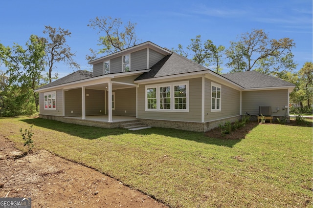 243 Barrington Oaks Dr, Brunswick, GA 31523 - back of property featuring roof with shingles, central AC unit, and a lawn