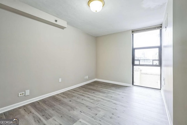 620 Peachtree St NE Unit 1413, Atlanta, GA 30308 - unfurnished room with baseboards, wood finished floors, and a wall of windows