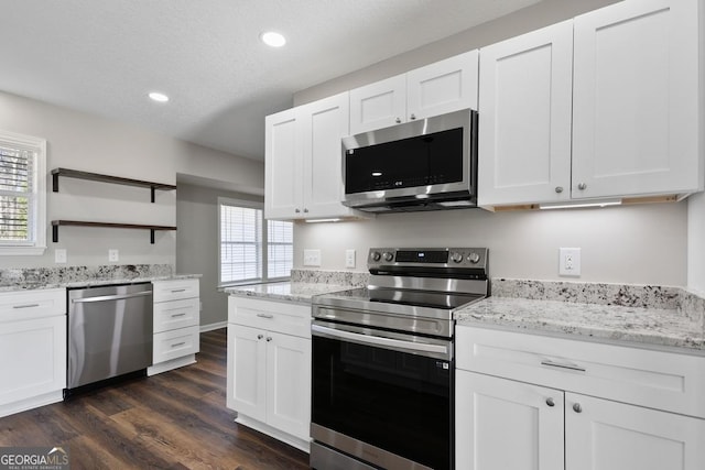 kitchen with white cabinets, stainless steel appliances, dark wood-style floors, and a wealth of natural light