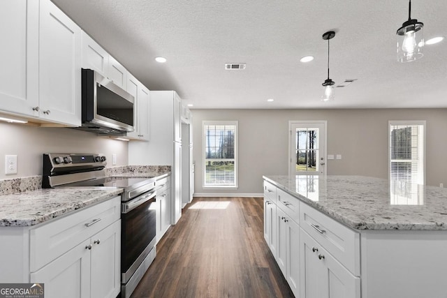 kitchen with a textured ceiling, white cabinets, a kitchen island, dark wood finished floors, and appliances with stainless steel finishes