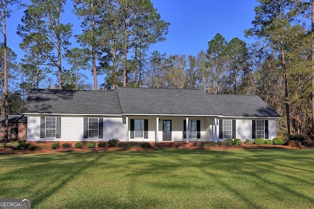ranch-style home featuring a front lawn, covered porch, and roof with shingles
