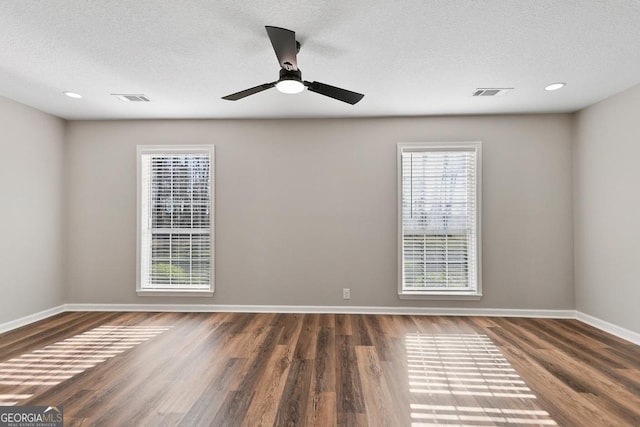 unfurnished room with baseboards, a textured ceiling, visible vents, and wood finished floors