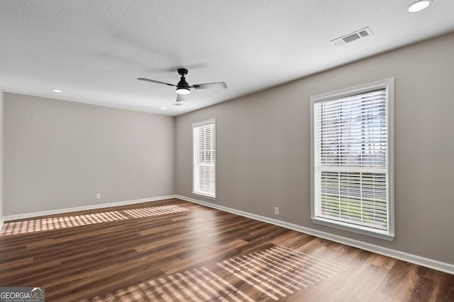 unfurnished room featuring a ceiling fan, wood finished floors, a textured ceiling, baseboards, and visible vents