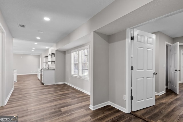 hall featuring dark wood-style floors, baseboards, and a sink