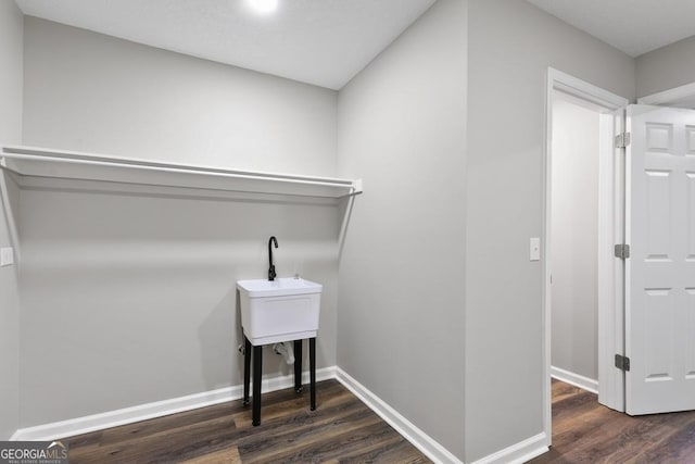 clothes washing area with baseboards, wood finished floors, and laundry area