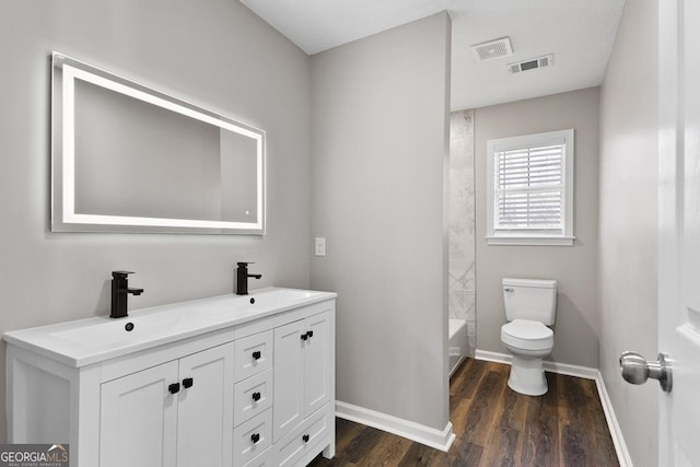 bathroom featuring wood finished floors, a sink, toilet, and visible vents