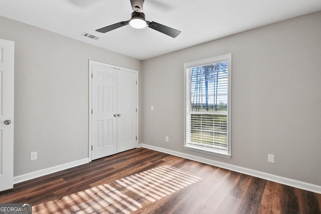 unfurnished bedroom featuring baseboards, visible vents, a closet, and wood finished floors
