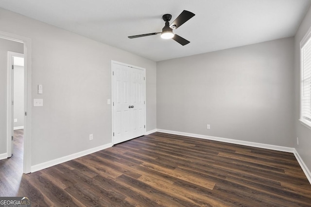 unfurnished bedroom featuring dark wood-style floors, multiple windows, ceiling fan, and baseboards
