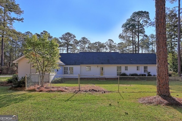 rear view of house with fence and a yard