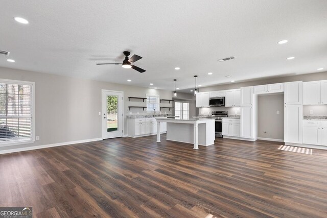 unfurnished living room with baseboards, visible vents, ceiling fan, and dark wood-style flooring