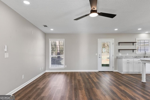 interior space with a sink, dark wood-style flooring, visible vents, and plenty of natural light