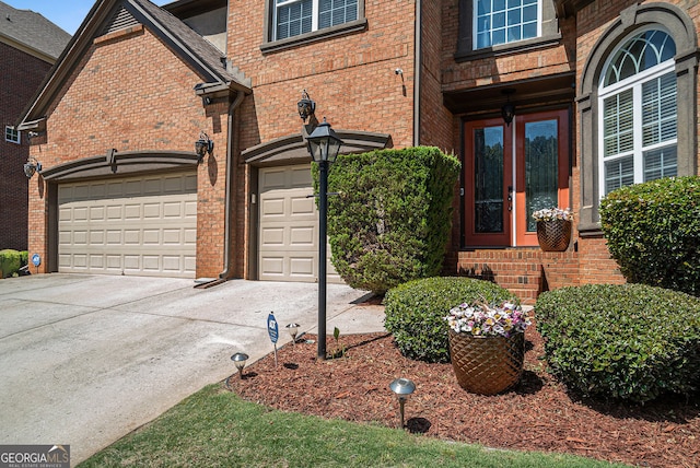 entrance to property with brick siding, driveway, and a garage