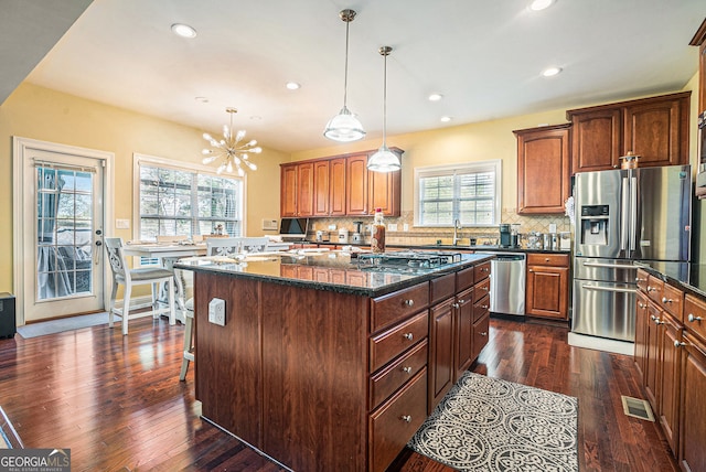 kitchen with decorative backsplash, stainless steel appliances, visible vents, and a kitchen island
