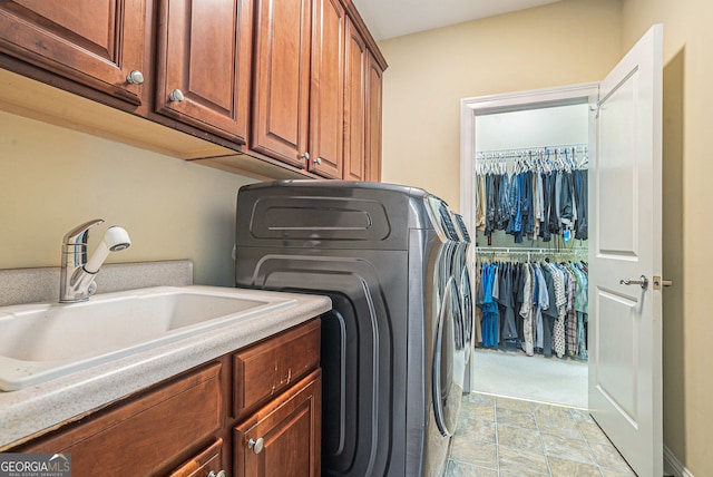 washroom featuring stone finish flooring, washer / clothes dryer, cabinet space, and a sink