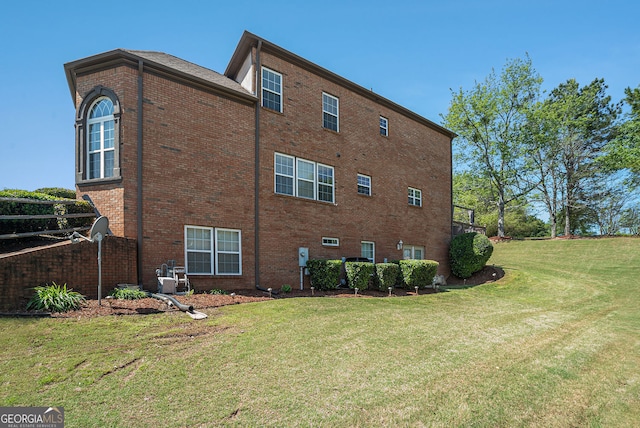 view of property exterior featuring brick siding and a yard