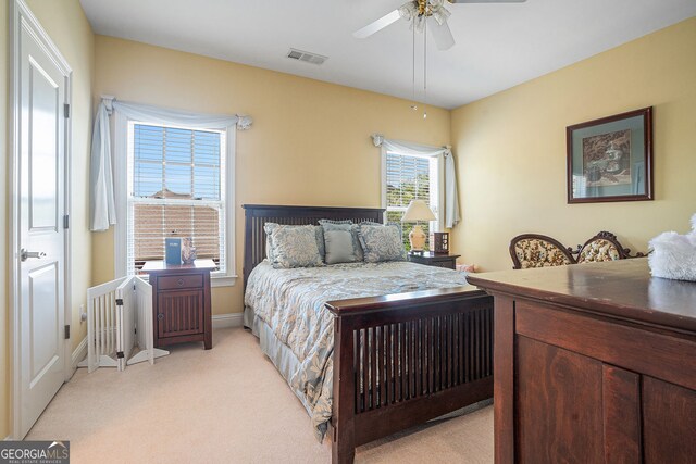 bedroom with radiator heating unit, visible vents, a ceiling fan, baseboards, and light colored carpet