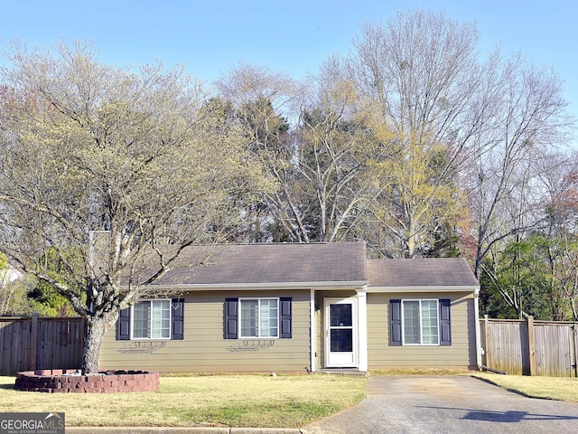 ranch-style house with a front yard, driveway, and fence