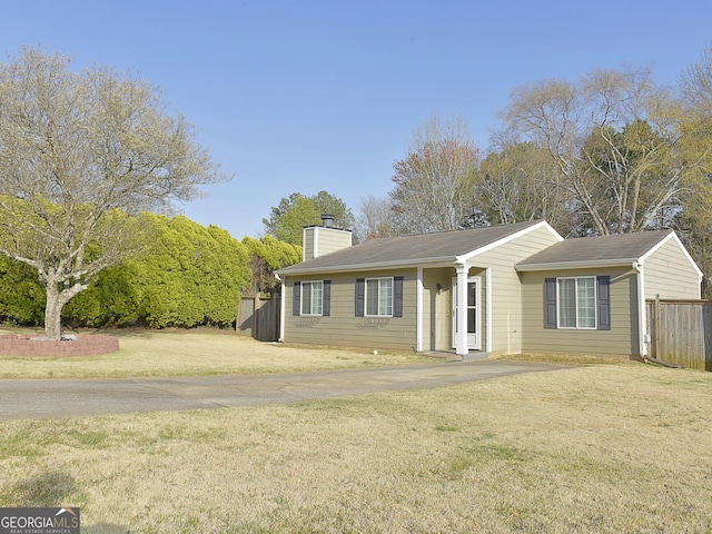 view of front of house with a chimney, fence, and a front lawn