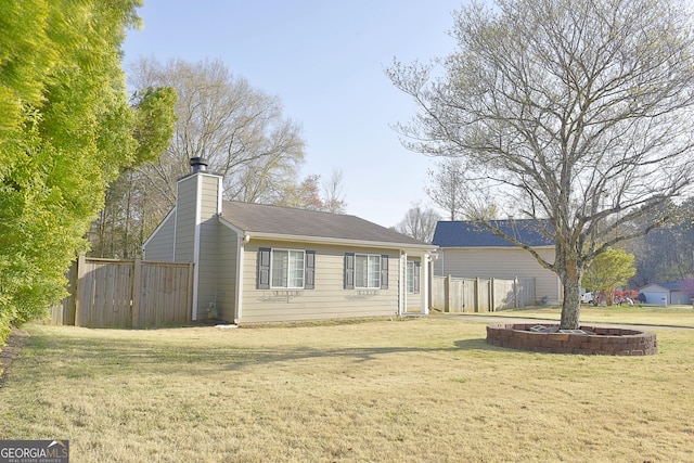 rear view of property featuring a chimney, fence, and a lawn