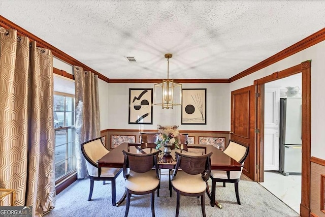 dining area with wainscoting, a notable chandelier, crown molding, and visible vents