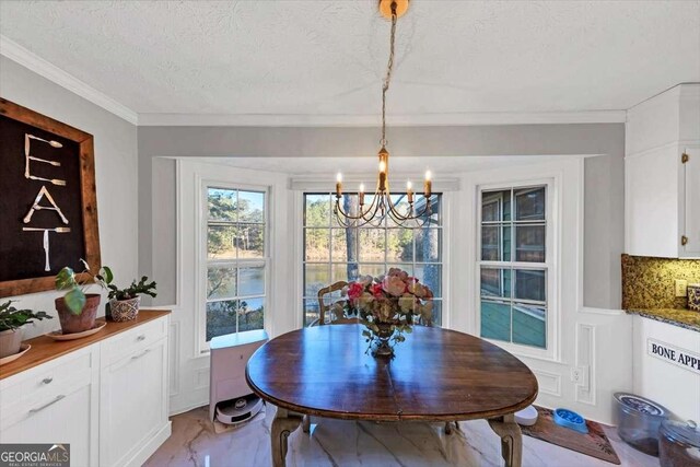 dining area with a textured ceiling, marble finish floor, ornamental molding, and an inviting chandelier