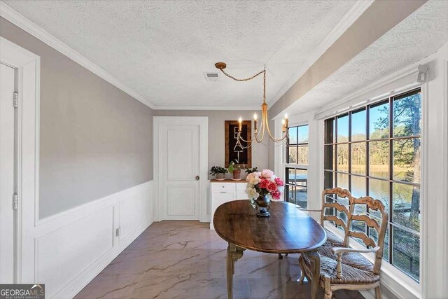 dining space featuring marble finish floor, a textured ceiling, a chandelier, and wainscoting